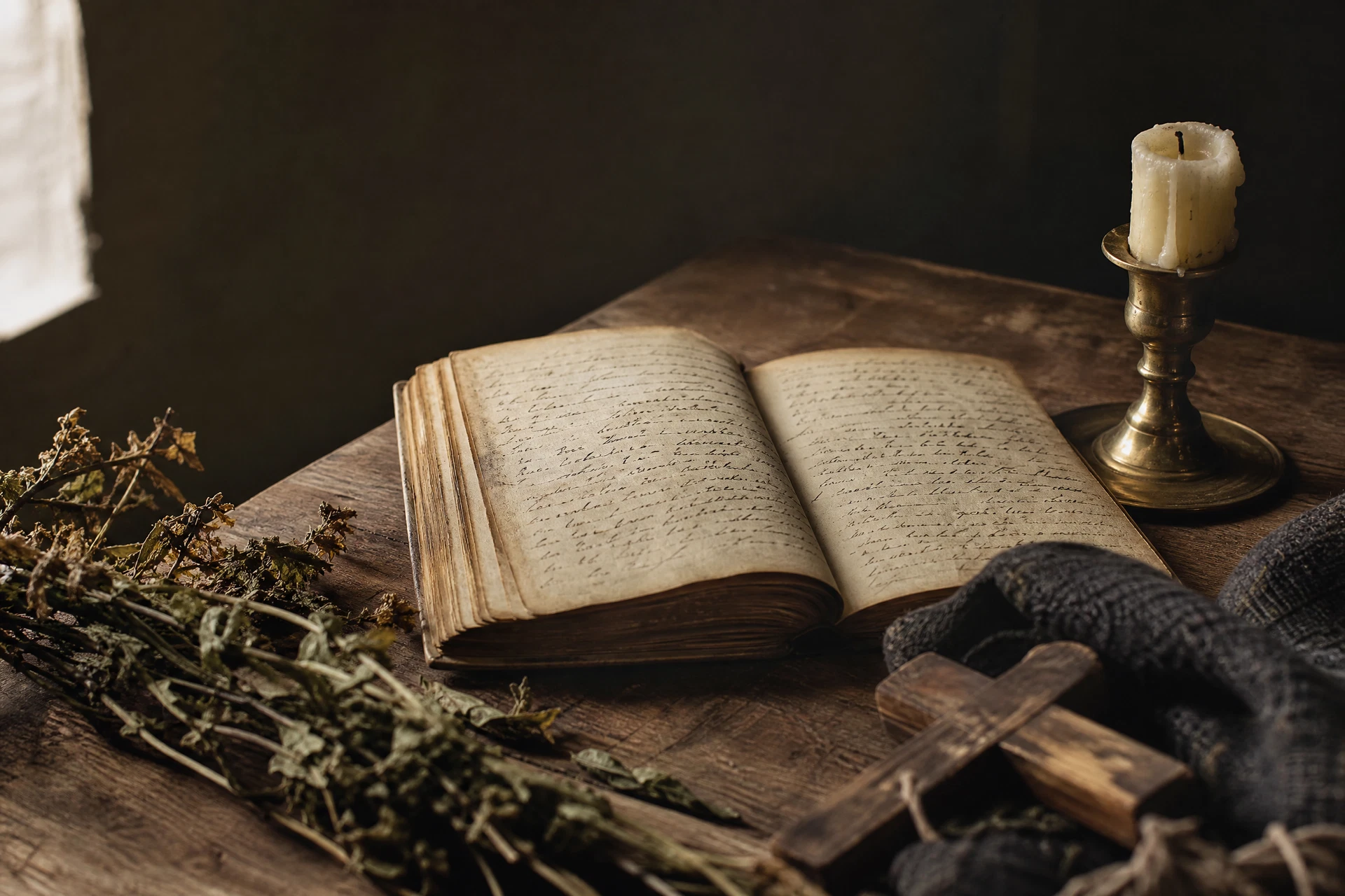 Caderno manuscrito, vela acesa e objetos sobre uma mesa de madeira